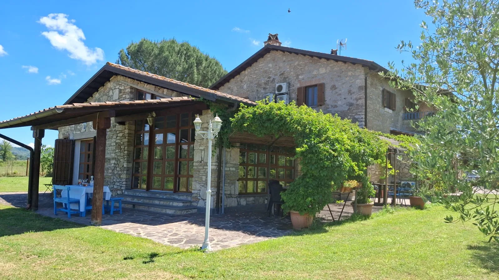 Facciata in pietra del casale Tuscia Prestige con veranda e giardino