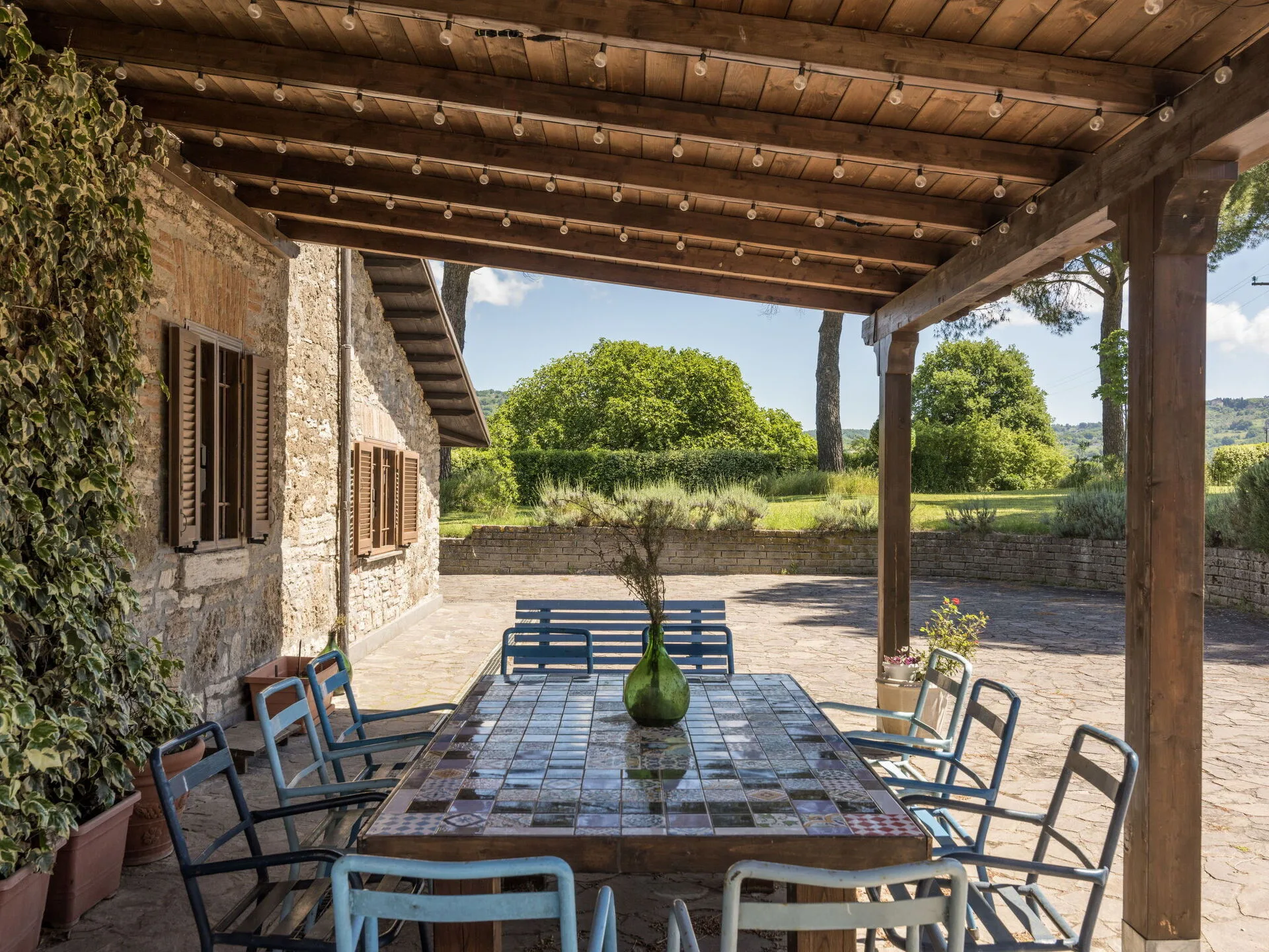 Veranda del casale Tuscia Prestige con tavolo in maiolica e vista sul giardino